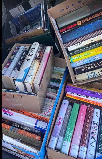 Open boxes of donated books, mostly hardcover fiction and non-fiction, sorted and ready to go through.